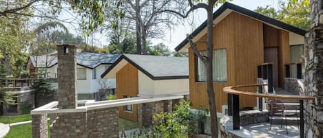 A modern house with a stone chimney, a wooden deck, and a stone wall.