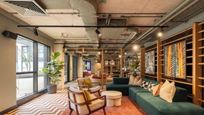 A modern lounge area with seating, a coffee table, and a large potted plant. - Charles Hope Apartments - Leeds (Leeds)