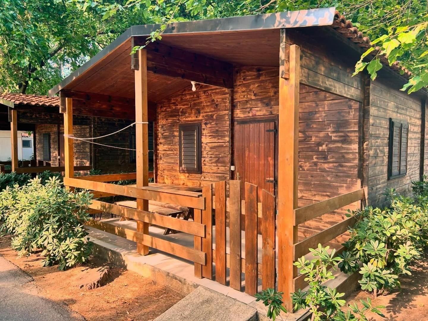 A wooden cabin with a porch, a door, and a window.