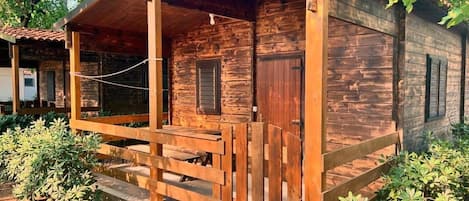 A wooden cabin with a porch, a door, and a window.