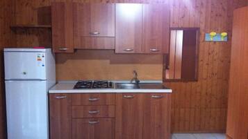 Una cucina con mobili in legno, un frigorifero bianco, un fornello e un lavello.