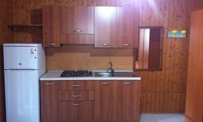 A kitchen with wooden cabinets, a white refrigerator, a stove, and a sink.