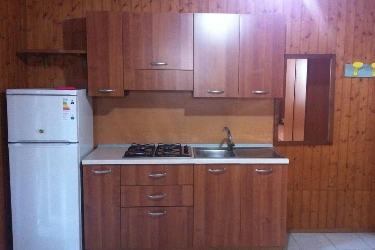 Una cocina con armarios de madera, un refrigerador blanco, una estufa y un lavaplatos.