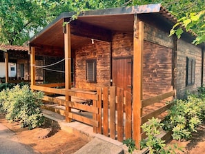 A wooden cabin with a porch, a door, and a window.