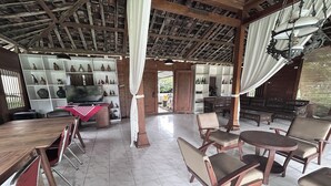 A spacious room with a wooden ceiling, tiled floor, and a variety of chairs and tables. - Carla Garden By Zuzu (Pakem)