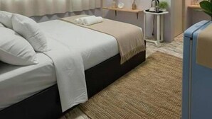 A bedroom with a bed, a bedside table, an air conditioning unit, a small desk, a plant, and a door. - Saan Stay  (Krabi)