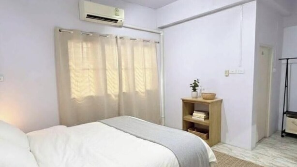 A bedroom with a bed, a shelf with a plant, and a door leading to another room. - Saan Stay  (Krabi)