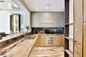 A modern kitchen with a marble countertop, built-in oven, and contemporary cabinetry. - High End Holiday Homes (Dubai)