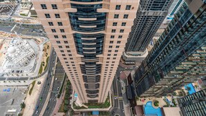 A high-rise building with multiple floors, a central courtyard, and surrounding roads. - High End Holiday Homes (Dubai)