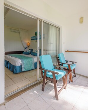 A room with a bed, a sliding glass door leading to a balcony with two chairs and a table. - Heritage Hotels Ltd (Mombasa)