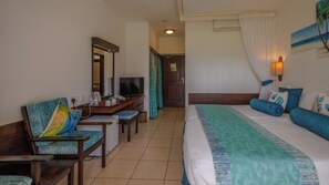 Habitación de hotel con cama, escritorio con televisor, una silla y baño visible a través de una puerta abierta.