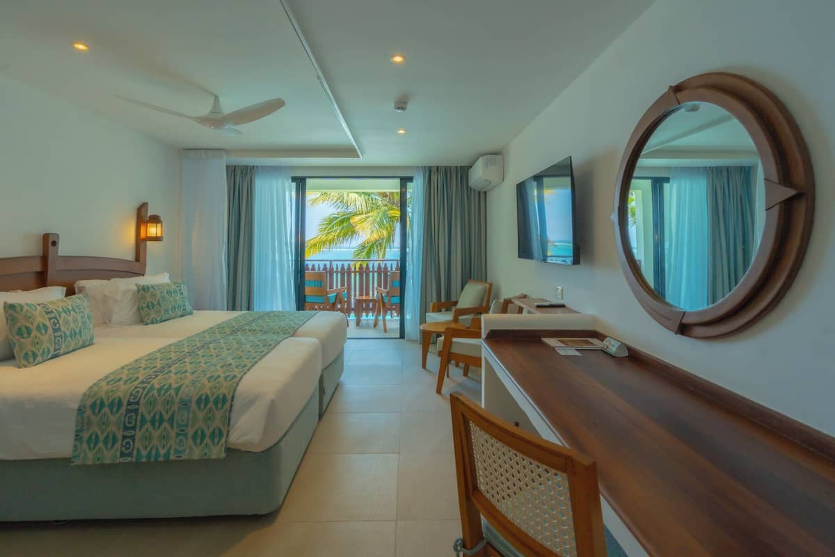 Een hotelkamer met een bed, bureau, stoelen, een televisie en een balkon met uitzicht.