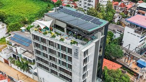 Un edificio de varios pisos con jardín en la azotea y paneles solares.