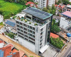 Un edificio de varios pisos con jardín en la azotea y paneles solares.