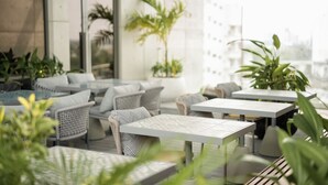 Un área de estar al aire libre con mobiliario de mimbre y plantas en macetas.