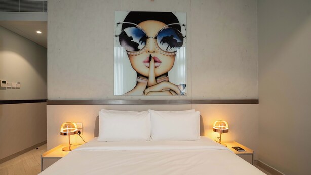 A hotel room with a large bed, two bedside tables with lamps, and a wall-mounted artwork above the bed. - Sesaya Poshtel & Bistro (Sri Jayawardenepura Kotte)