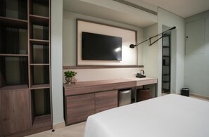 A modern bedroom with a bed, a TV mounted on the wall, a desk with a plant, and a wardrobe. - Sesaya Poshtel & Bistro (Sri Jayawardenepura Kotte)