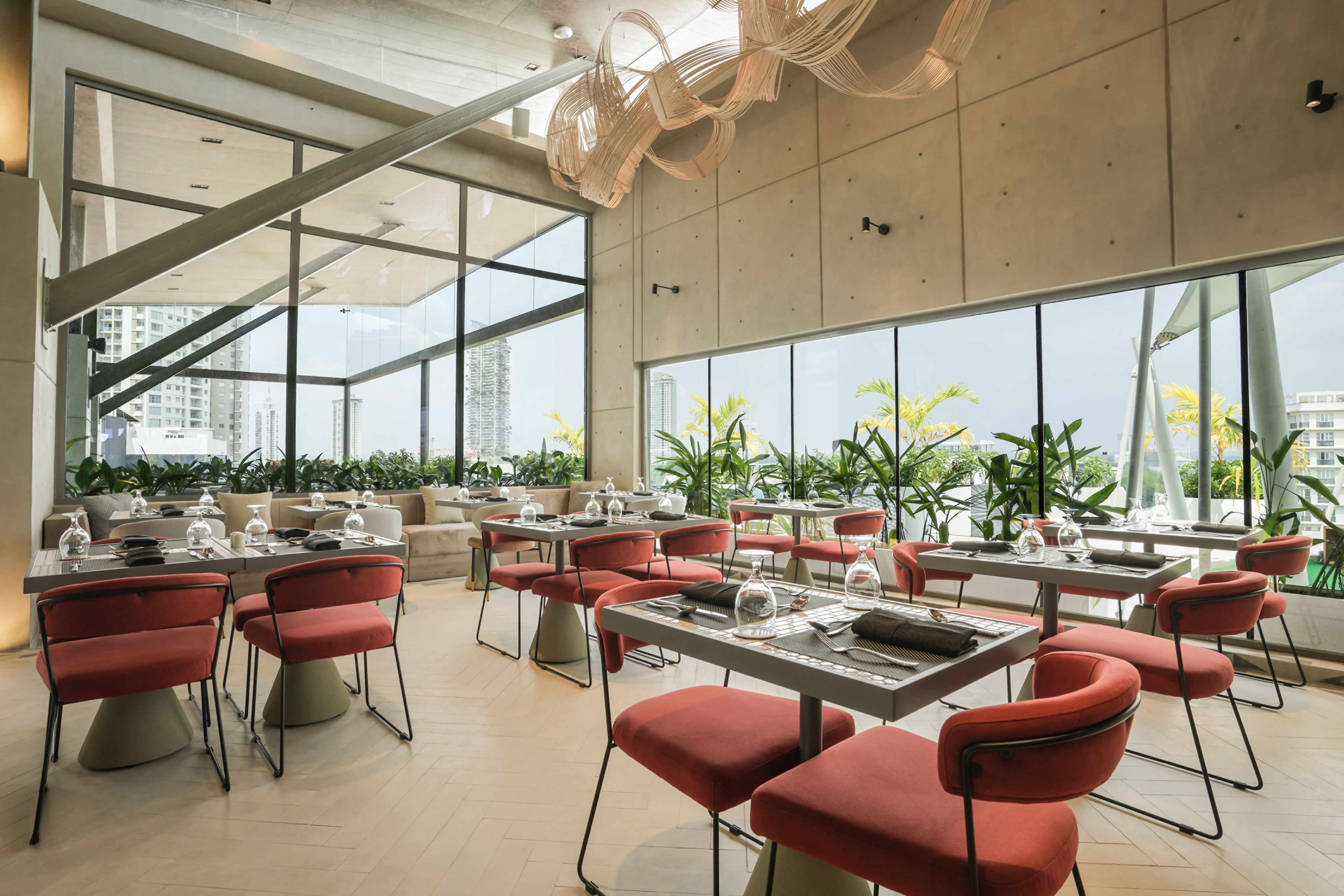 A modern dining area with tables and chairs, large windows, and a view of the cityscape.