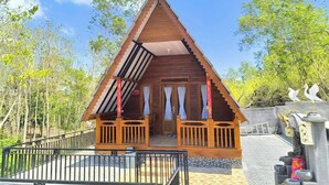 Una baita di legno con tetto a punta, un portico con ringhiere e una piccola terrazza.