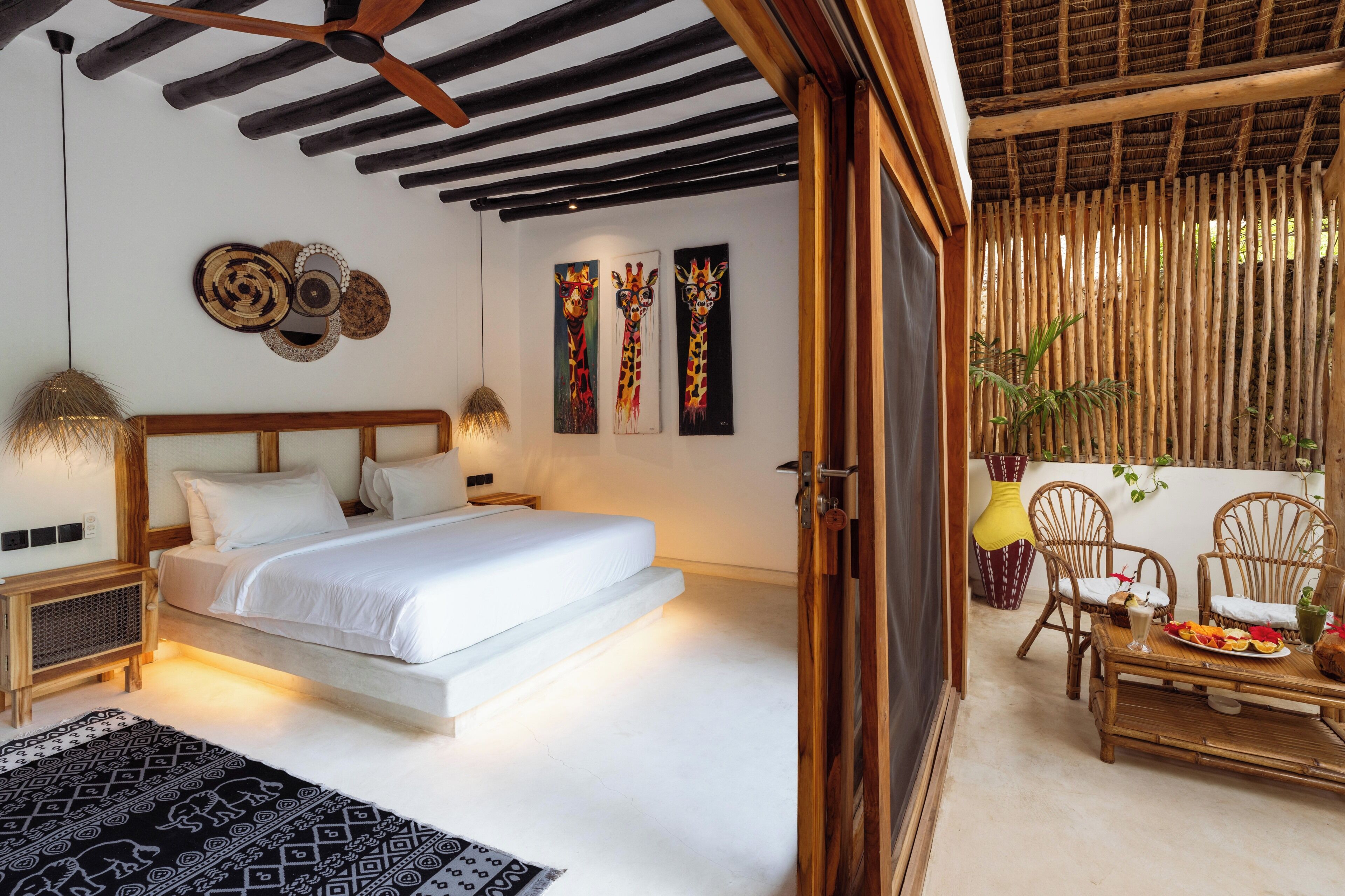 Un dormitorio con cama, mesitas de noche, decoración en la pared y vista a un comedor con sillas y una mesa.