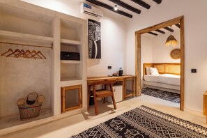 Habitació petita amb llit, escriptori, armari i penjador.