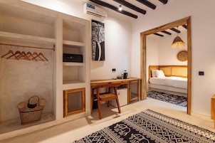 Una habitación pequeña con cama, escritorio, armario y perchero.