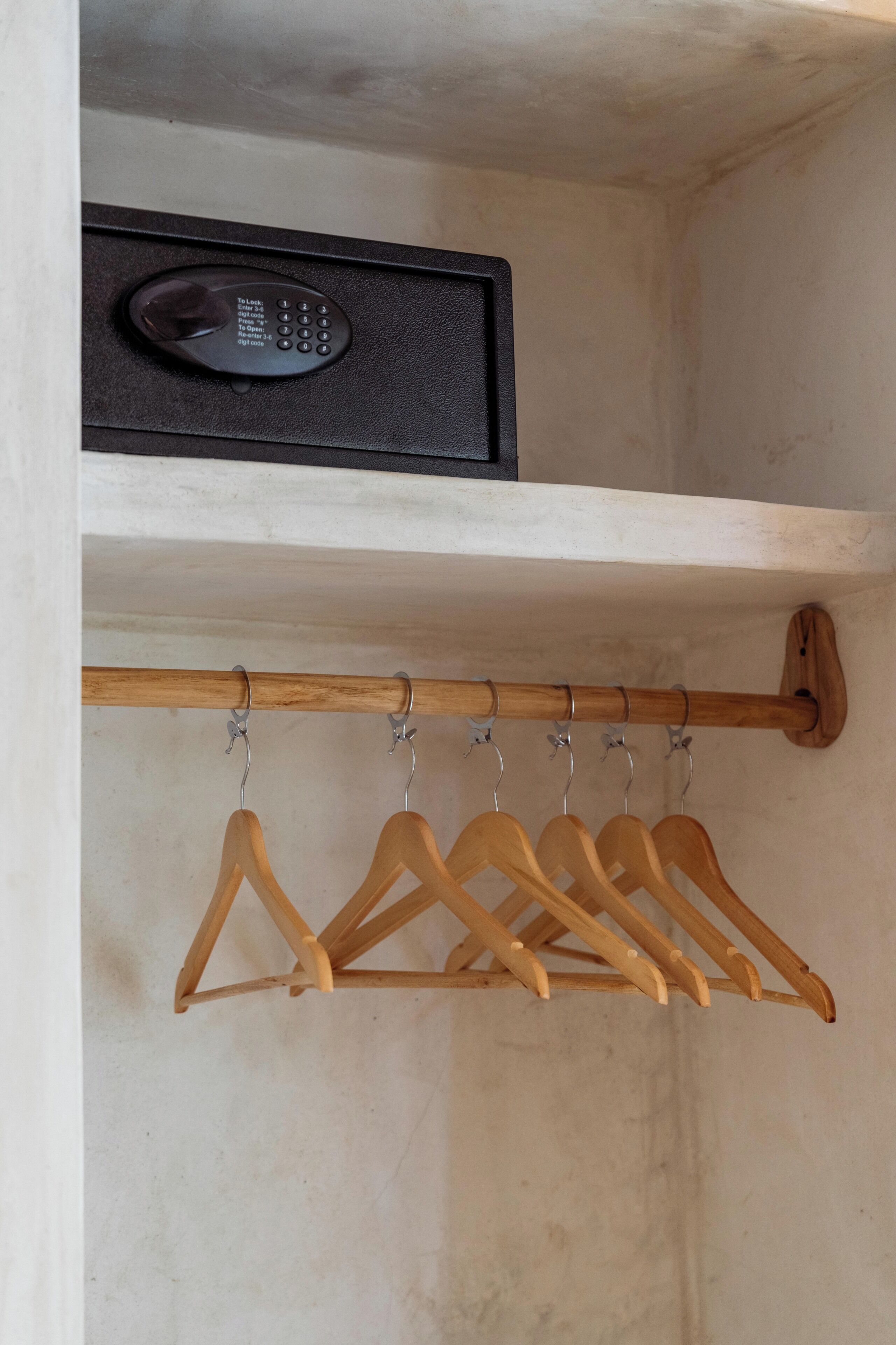 Un porte-manteau en bois, muni de cintres, et un appareil électronique noir placé au-dessus.