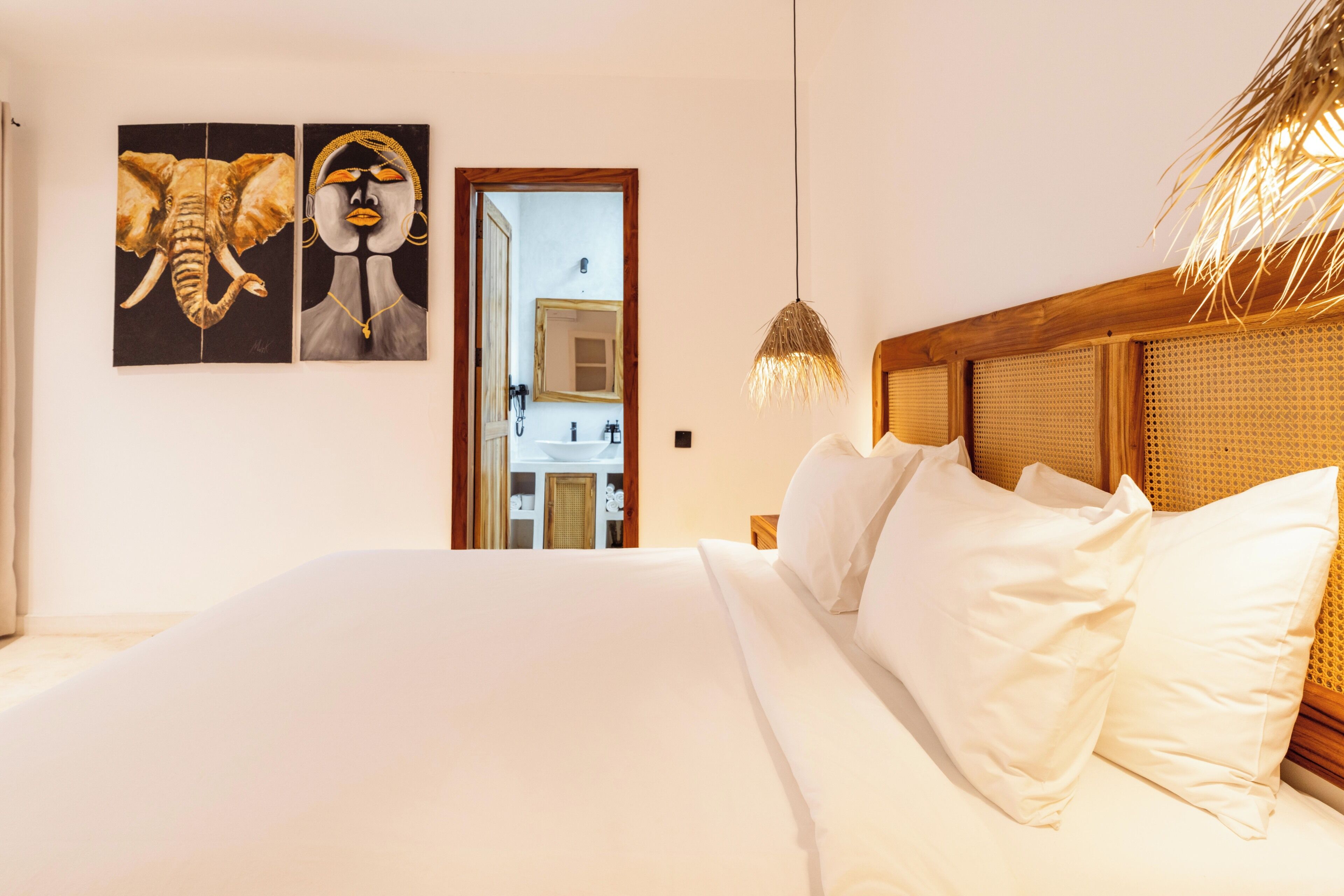 Un dormitorio con una cama grande, un cabecero de madera y dos cuadros colgados en la pared.