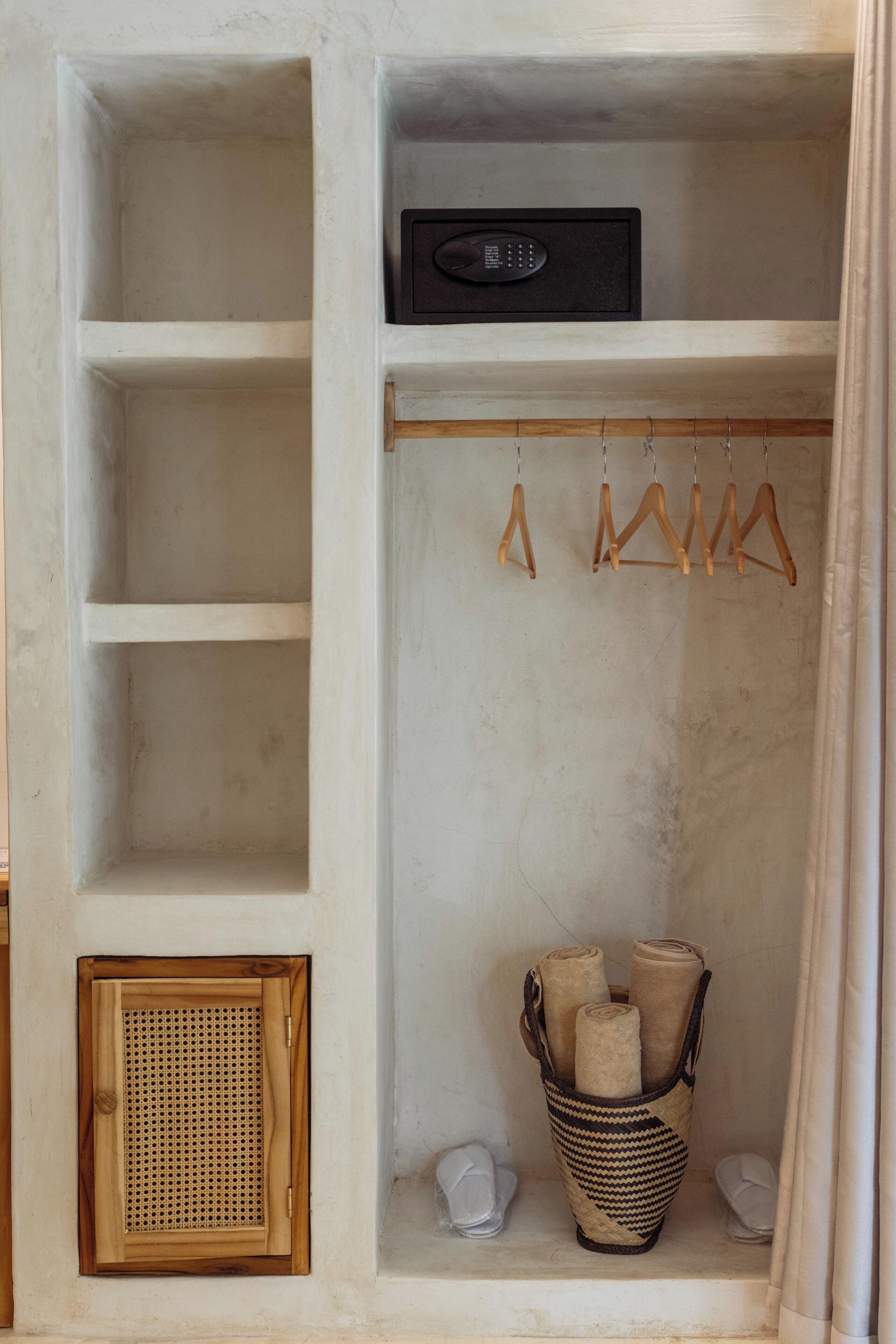 Uno spazio di deposito con scaffali, una radio, grucce di legno e un cesto con asciugamani arrotolati.
