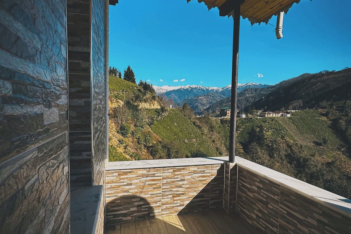 Ein Holzbalkon mit Steinmauern, der Blick auf eine Berglandschaft bietet.
