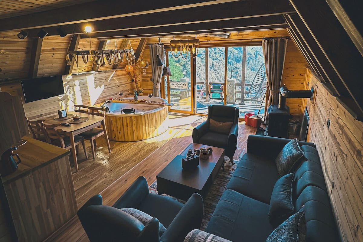 Ein gemütliches Holzhaus-Interieur mit Essbereich, Sofa und Kamin.