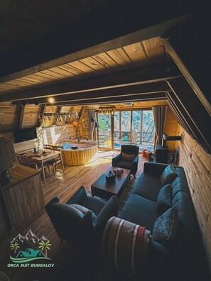 A cozy wooden cabin interior with a dining area, sofa, and a fireplace. - Orca Bungalows (Ardeşen)