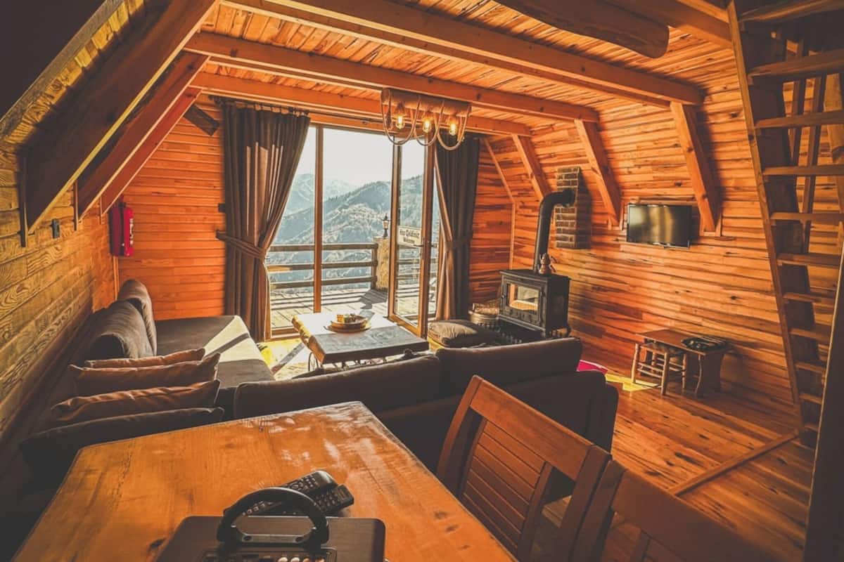 Ein gemütliches Blockhaus mit Schlafzimmer im oberen Bereich, Essbereich und Kamin.