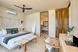 A bedroom with a bed, bedside table, laptop, and a surfboard. - Amina Wind Resort (La Ventana)