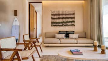Una sala de estar con sofá, sillas, una tabla de surf y un tapiz en la pared.