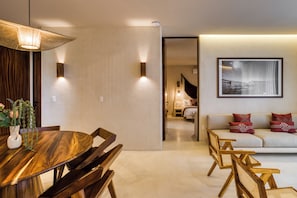 A modern living room with a sofa, wooden chairs, a dining table, and a wall-mounted picture. - Amina Wind Resort (La Ventana)