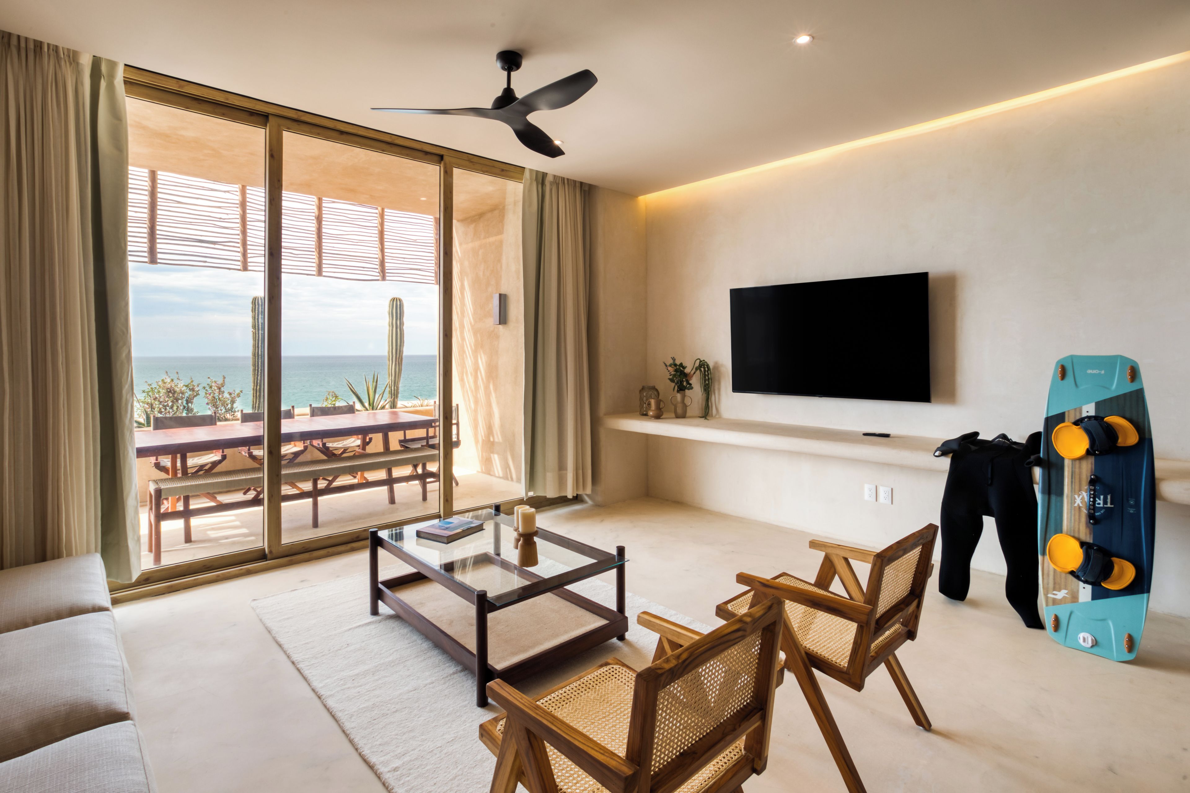 Een moderne woonkamer met een grote televisie, een glazen salontafel en uitzicht op de oceaan.