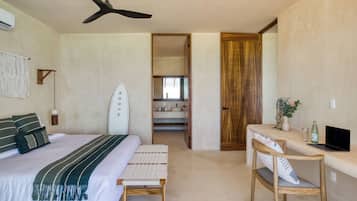 Un dormitorio con cama, escritorio, silla, una tabla de surf y ventilador de techo.