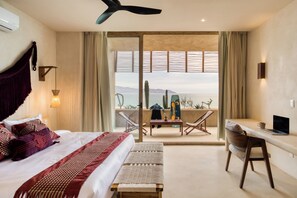 A hotel room with a bed, a desk, a laptop, and a view of the sea. - Amina Wind Resort (La Ventana)