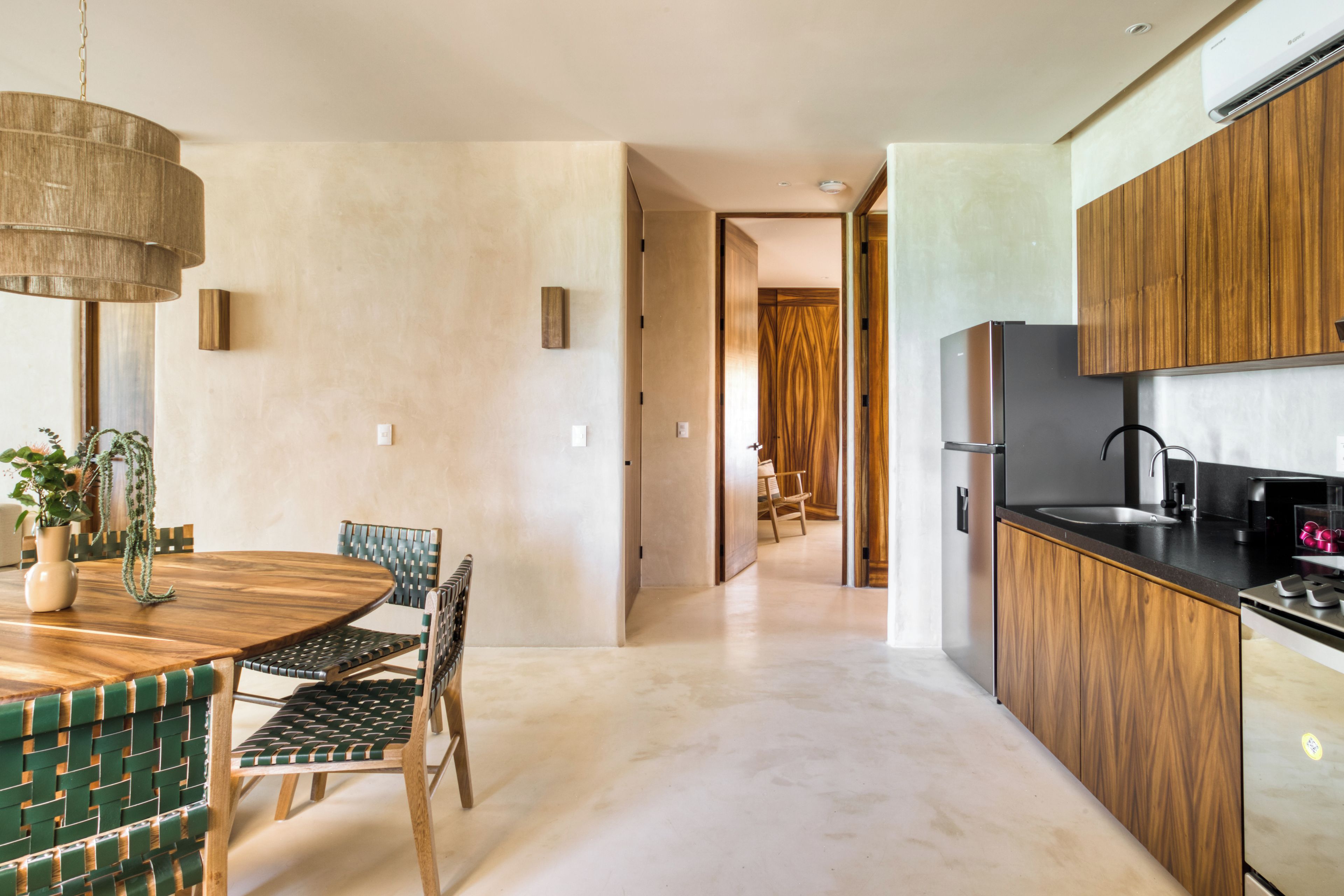 A modern kitchen with wooden cabinets, a stainless steel refrigerator, and a dining area with a round table and chairs.