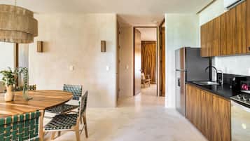 Una cocina moderna con armarios de madera, un refrigerador de acero inoxidable y un comedor con una mesa redonda y sillas.