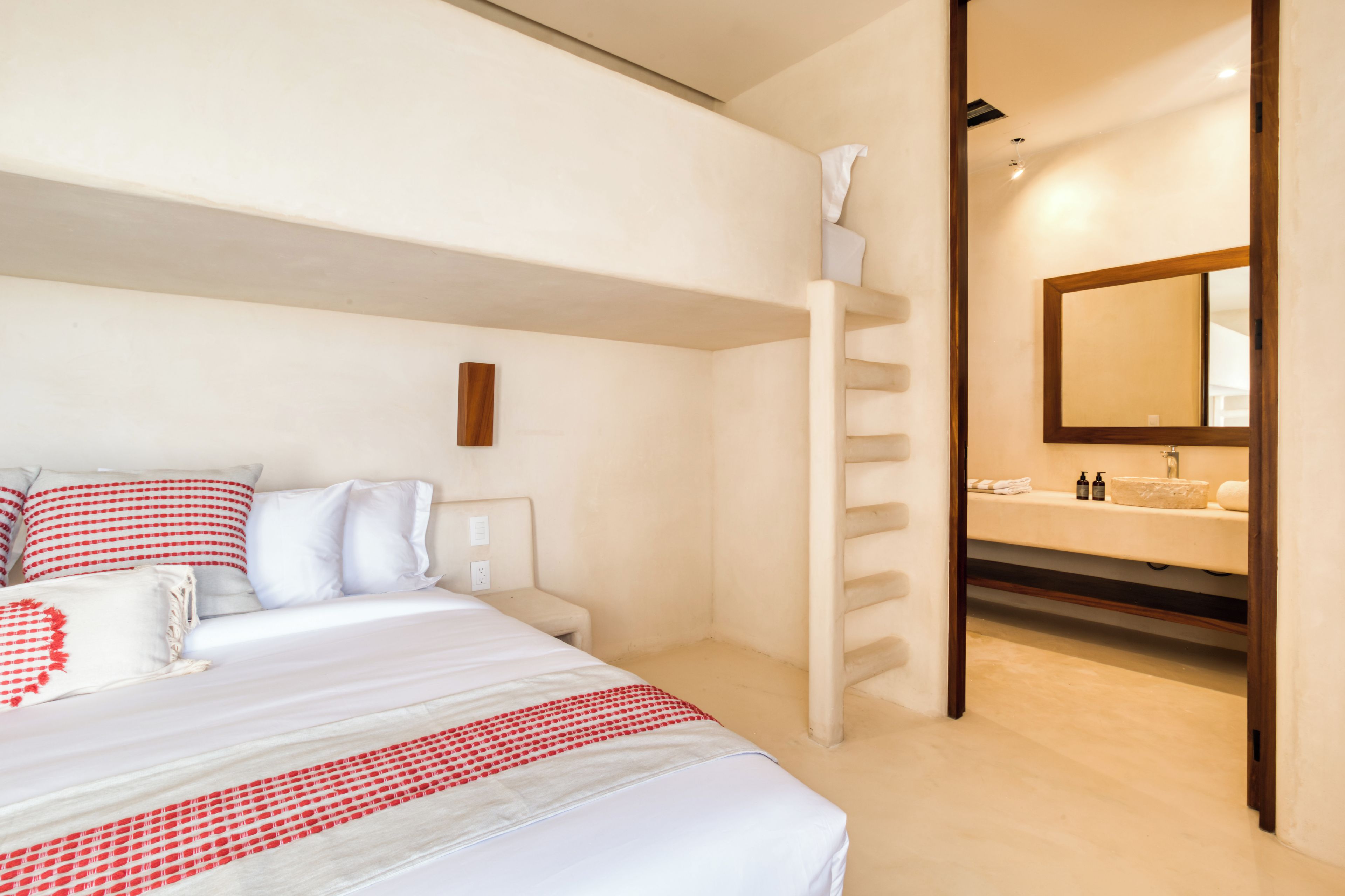 A hotel room with a bed, a bathroom with a mirror, and a towel rack.
