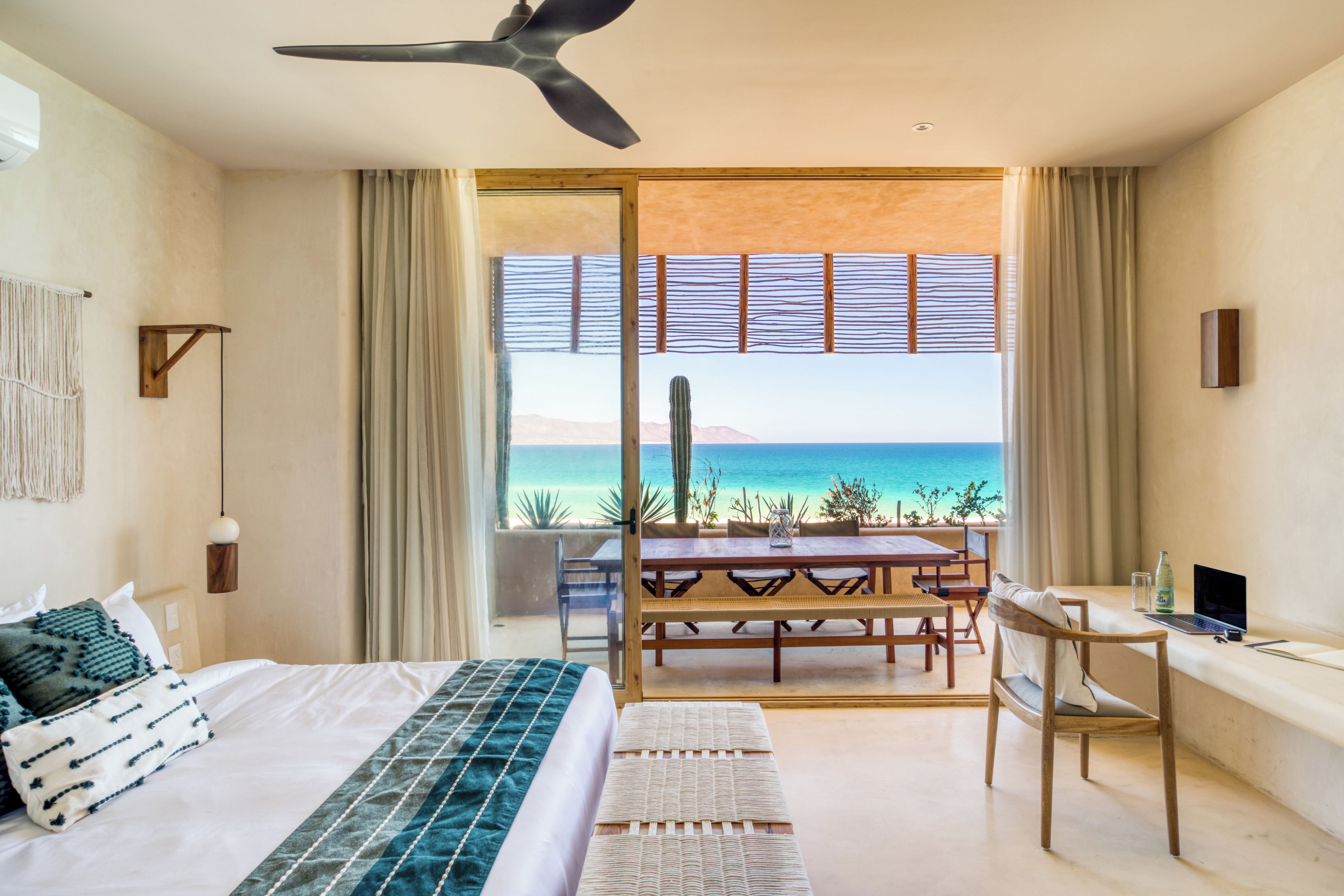 Ein Schlafzimmer mit Bett, Schreibtisch, Stuhl und Meerblick.