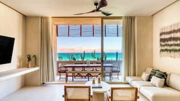 Una sala de estar moderna con comedor, ventanas grandes con vista al océano y un ventilador de techo.