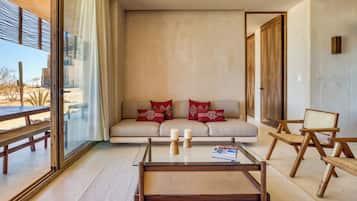 A modern living room with a glass coffee table, a sofa with red cushions, and wooden chairs.