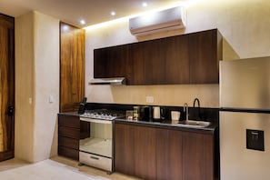 A modern kitchen with wooden cabinets, a built-in oven, and a stainless steel sink. - Amina Wind Resort (La Ventana)