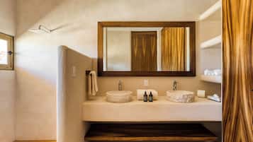 Un baño con un lavamanos redondo, dos espejos y estantes de madera.