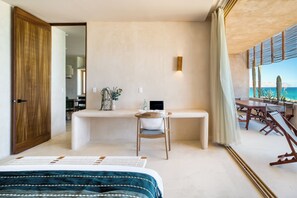 A bedroom with a bed, a desk, a chair, and a view of the sea. - Amina Wind Resort (La Ventana)