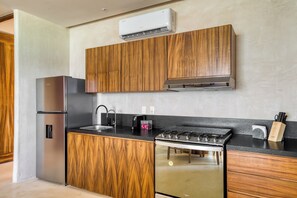 Una cocina moderna con armarios de madera, un refrigerador de acero inoxidable, una estufa a gas y un horno.