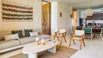 Una sala de estar moderna con un sofá, sillas, una mesa de centro y una zona de cocina con una mesa de comedor y sillas.